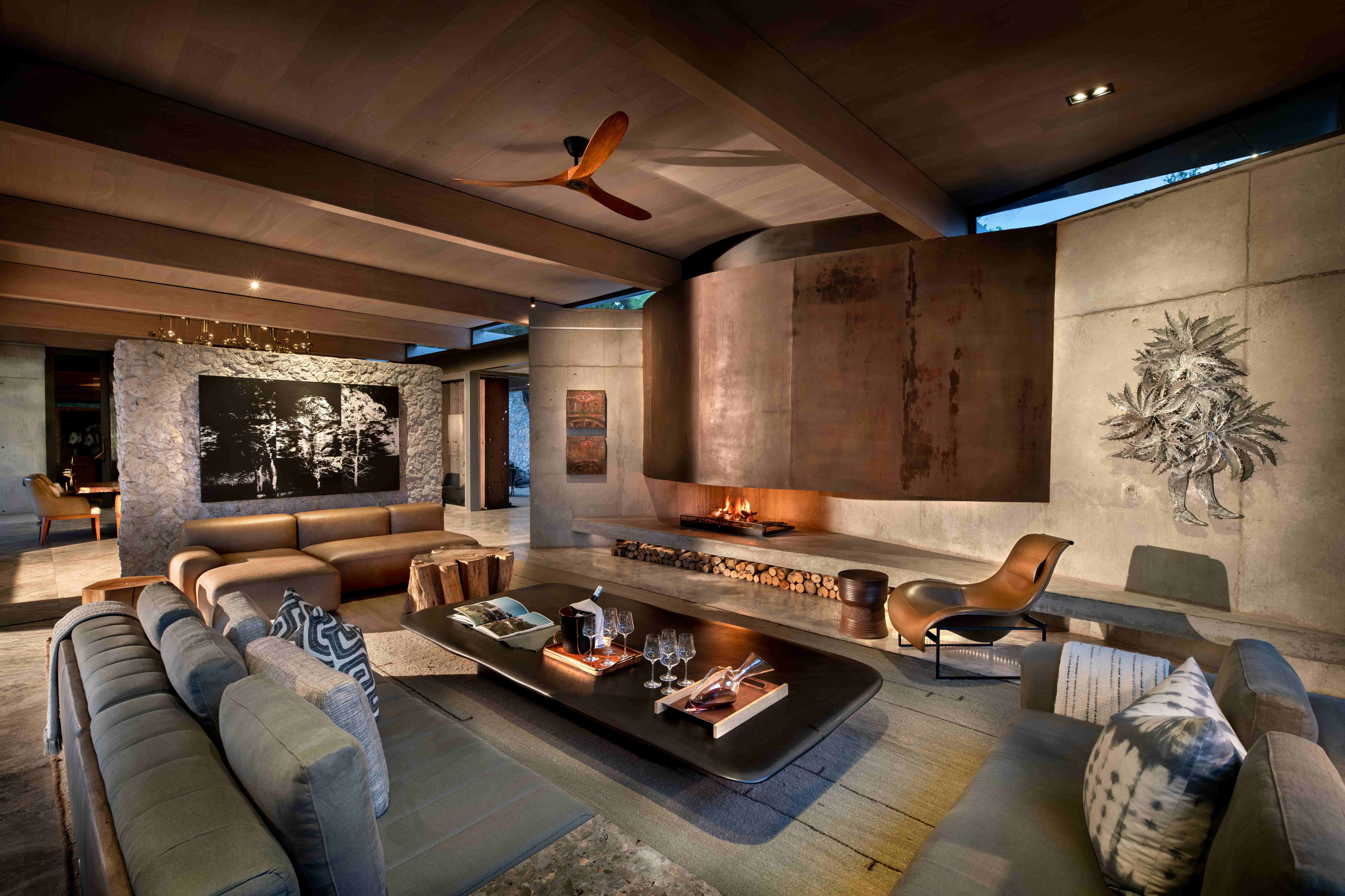 Sophisticated lounge interior with sculptural fireplace, contemporary curved seating, and refined earth-tone palette