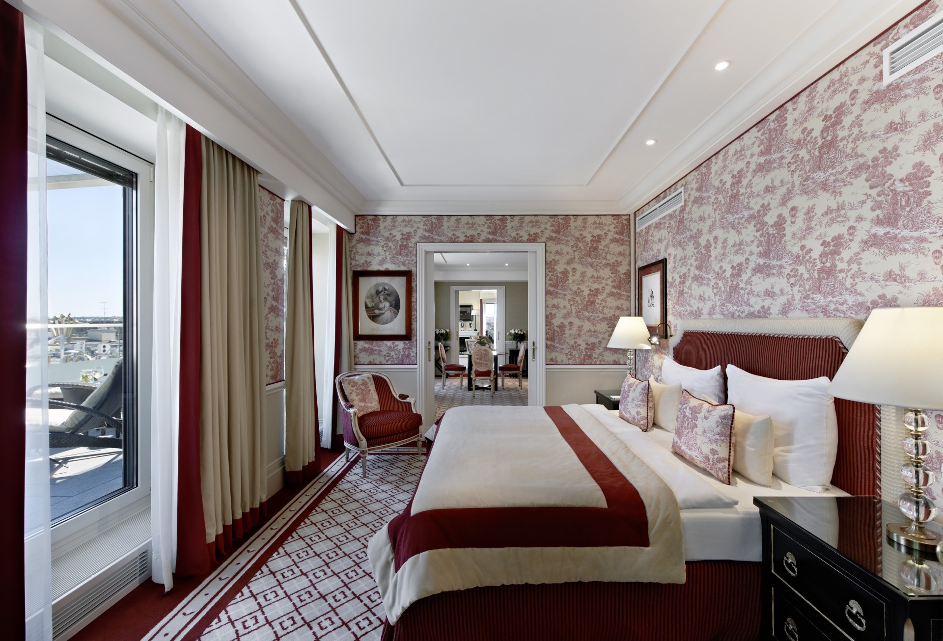 Luxurious Vienna bedroom with burgundy and cream toile wallpaper, king bed with burgundy headboard, and panoramic city views