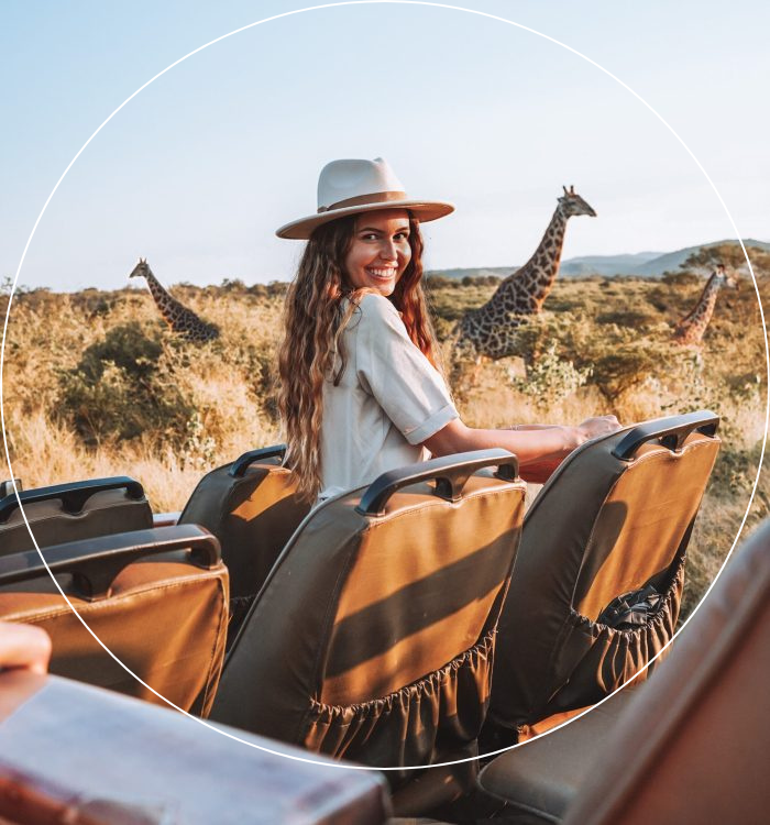 Woman on safari game drive with giraffes visible across the African savanna
