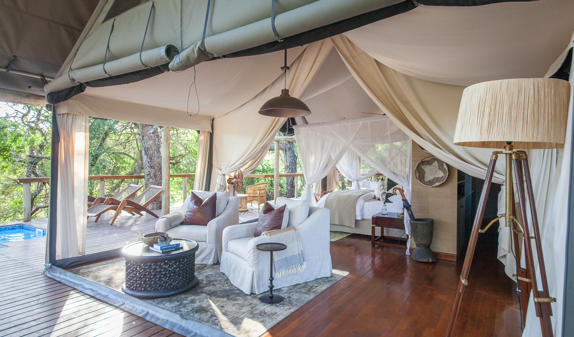 Luxury safari tent interior with cream canvas, flowing drapes, comfortable seating and bedroom area
